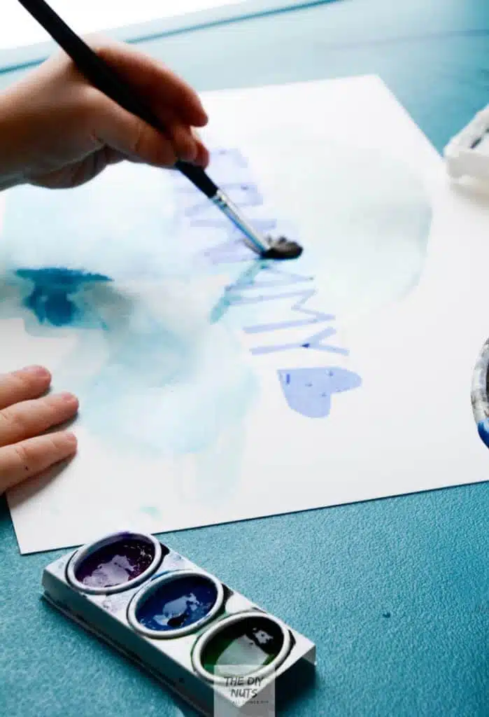grammy art project with child's hand using purple, blue and green watercolor paint