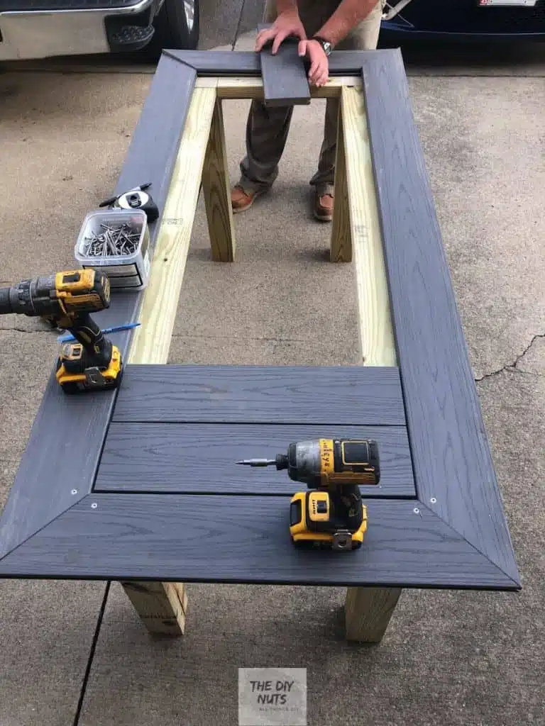 Smaller gray composite decking placed inside mitered table top frame on pressure treated wood base