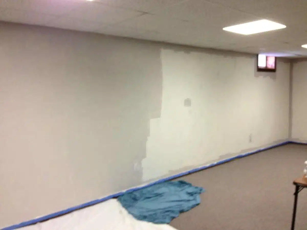 partially painted basement wall with grayish paint.