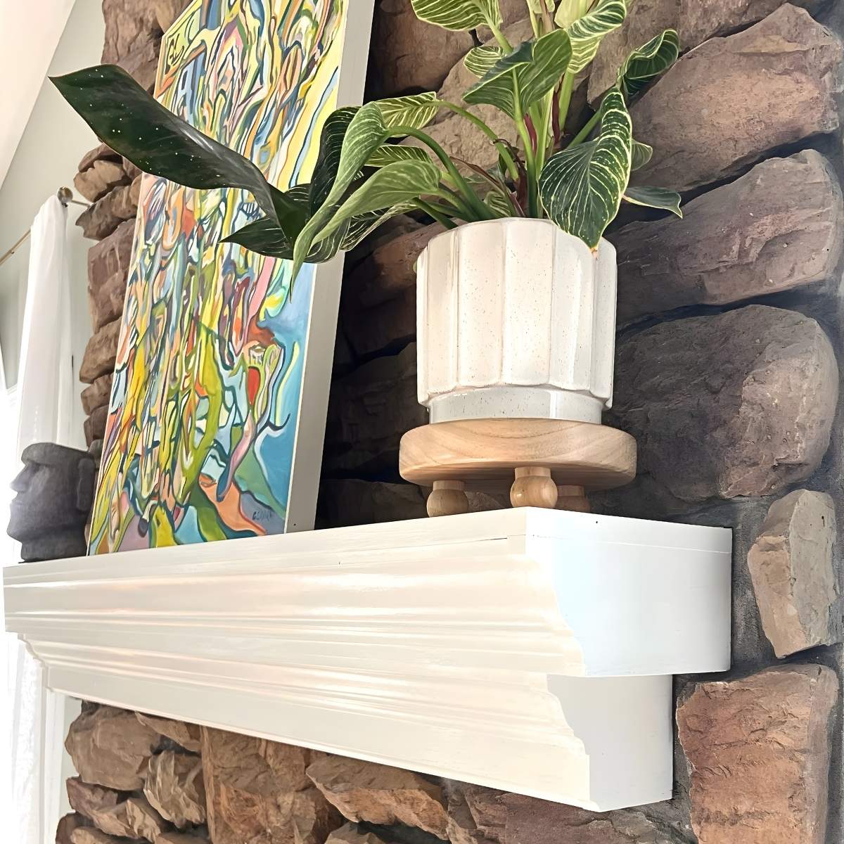 painted white mantel with plant and painting on it.