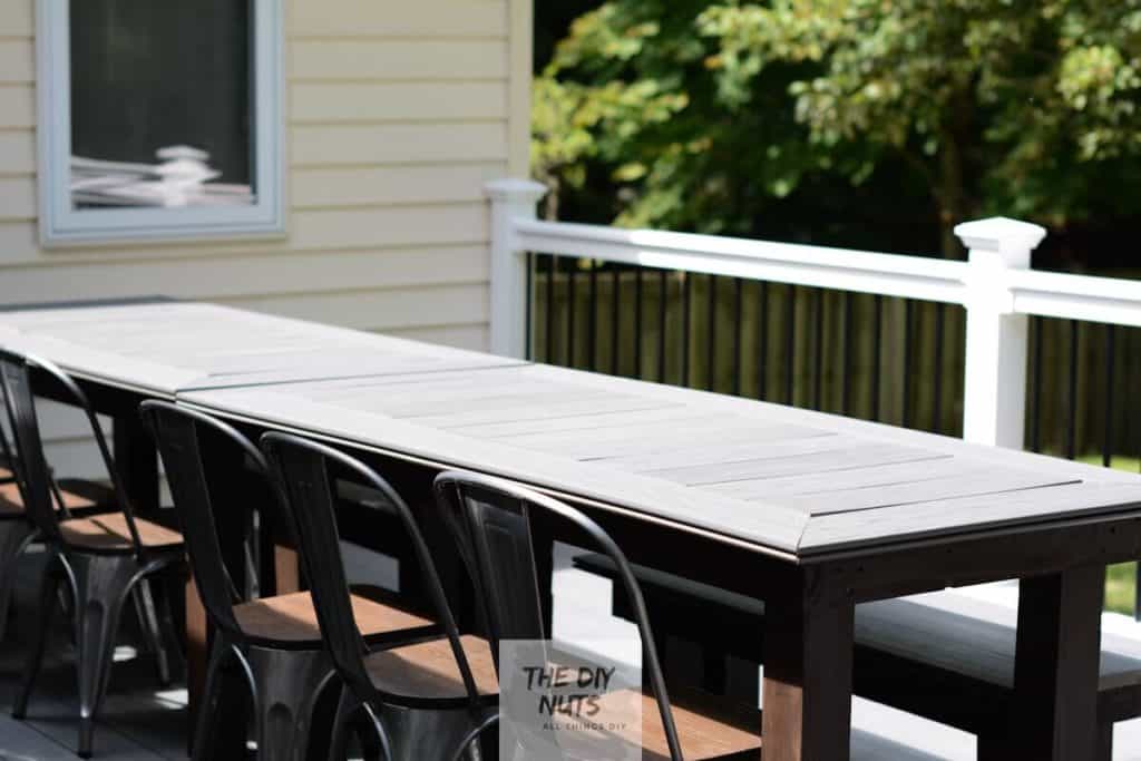 Large gray and DIY composite decking table with brown exterior stained legs with outdoor dining chairs.