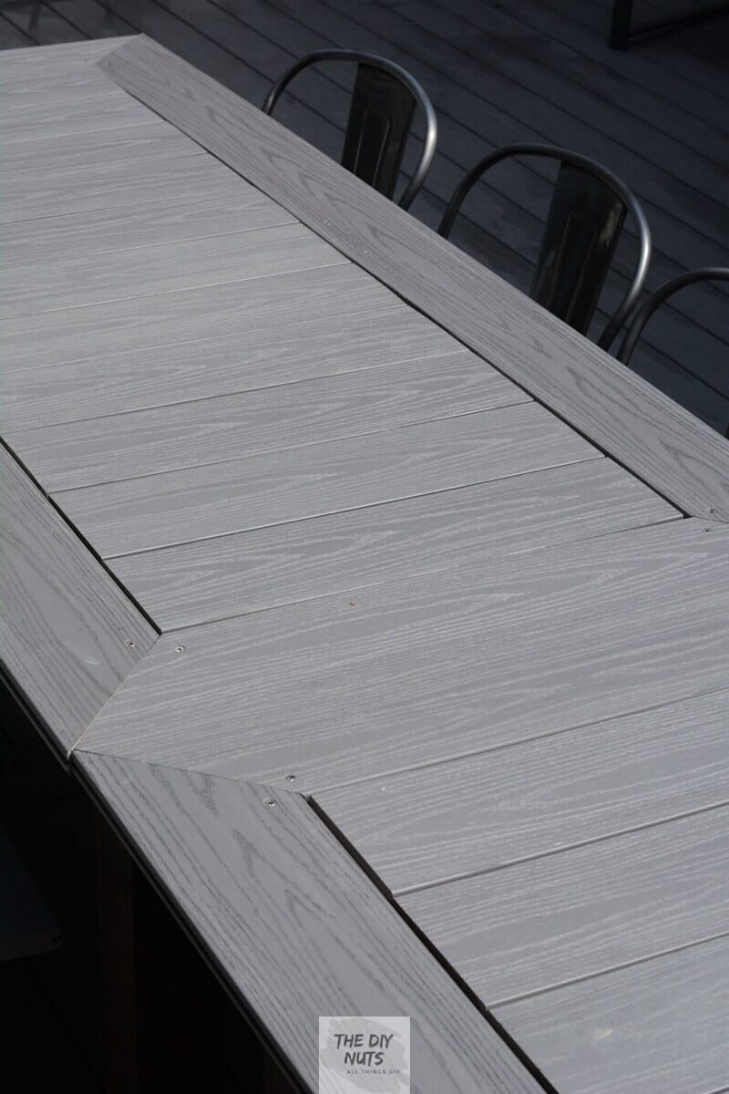 DIY outdoor table made with gray composite decking top with metal chairs. 