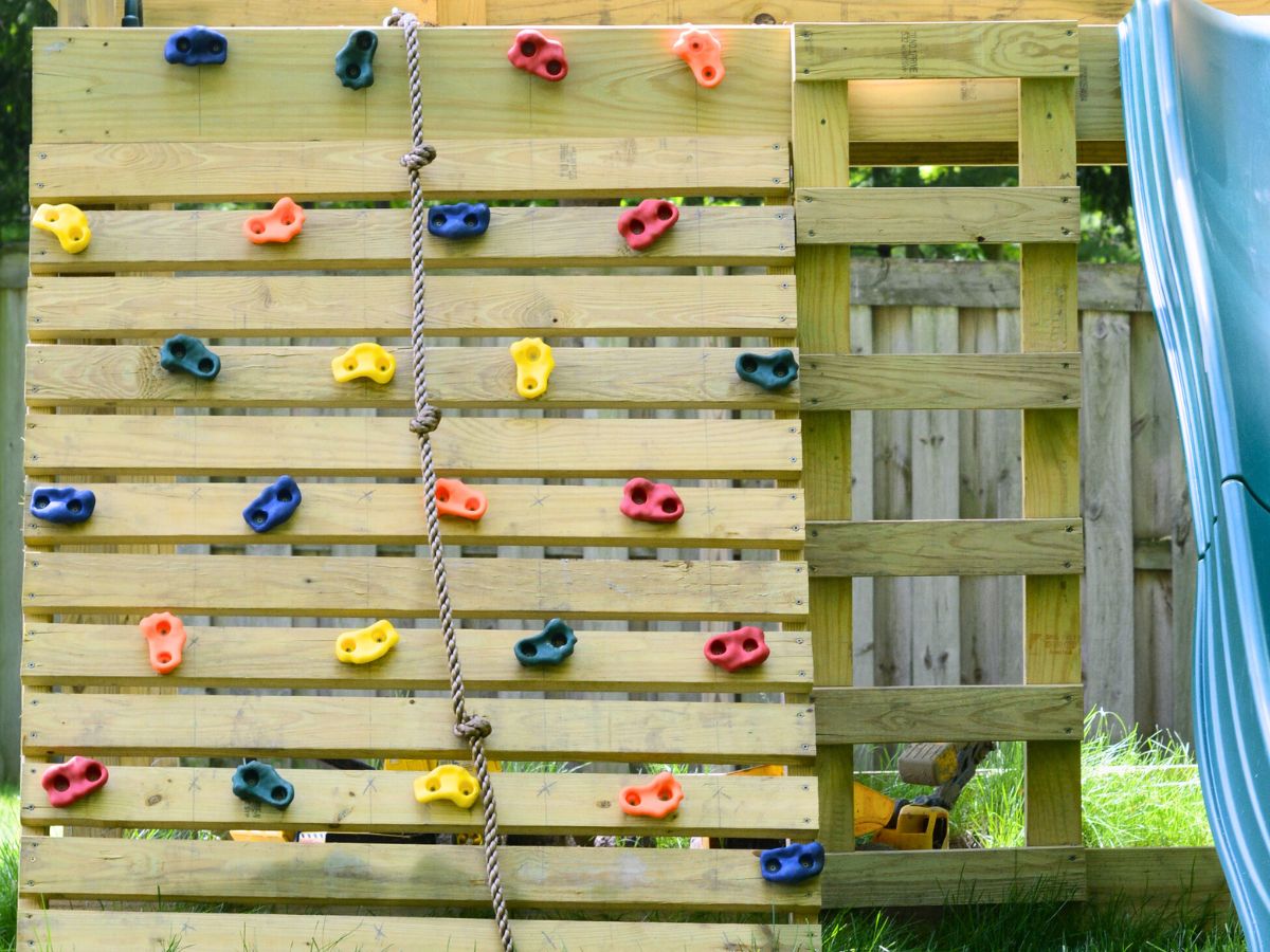 diy rock wall with colorful holds on playset with rope.