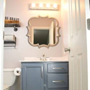 gray blue painted bathroom cabinets with mirror and painted light fixture.