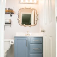 painted bathroom vanity cabinets with mirror and painted light fixture.