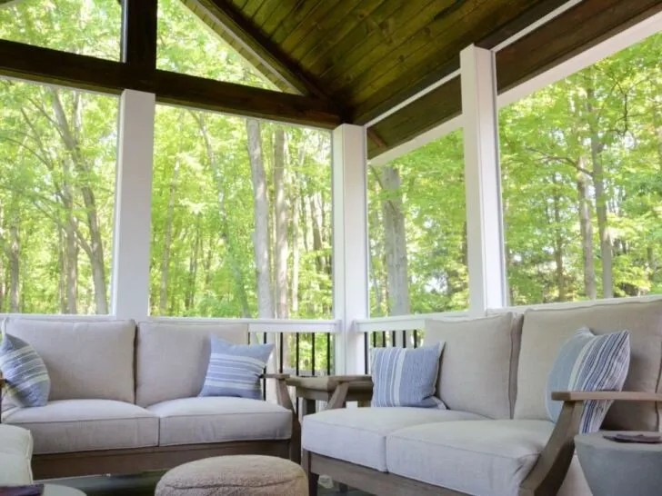 couches in screened-in porch with white columns and wood stained peaked ceiling.