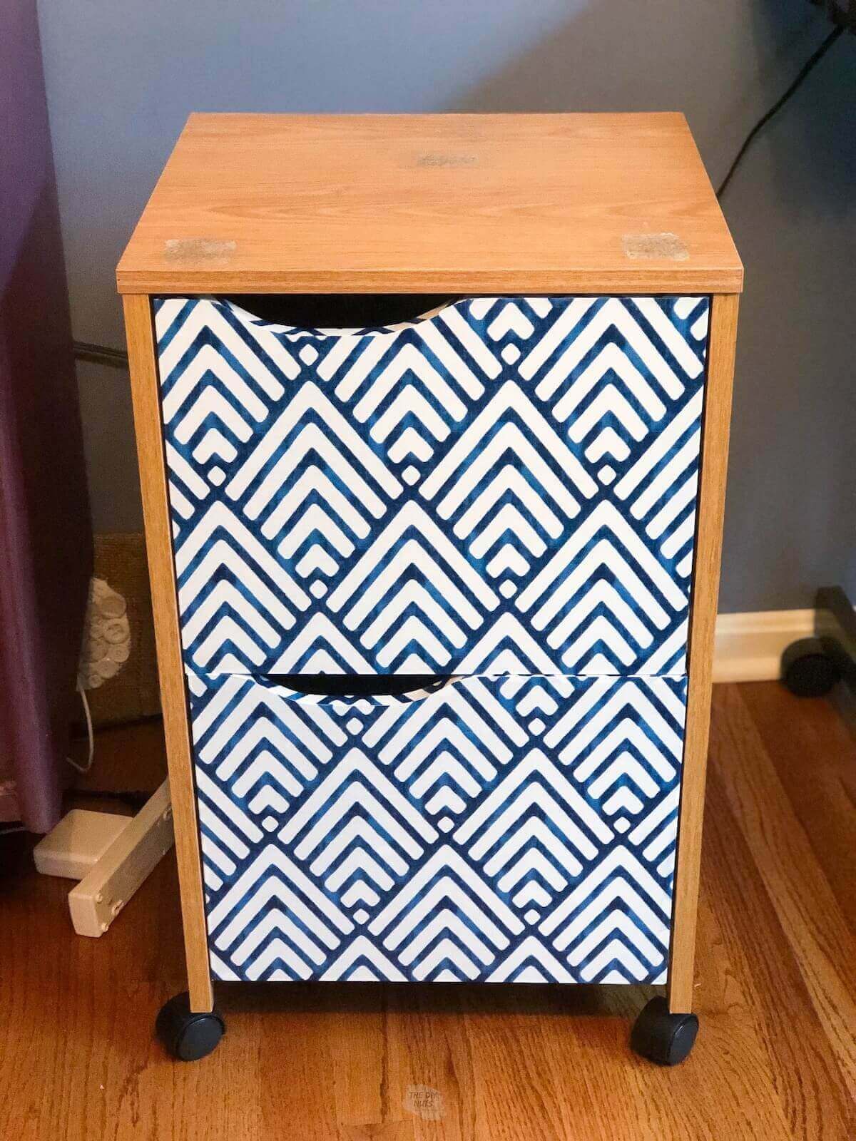oak file cabinet with drawers covered in blue and white patterned contact paper.