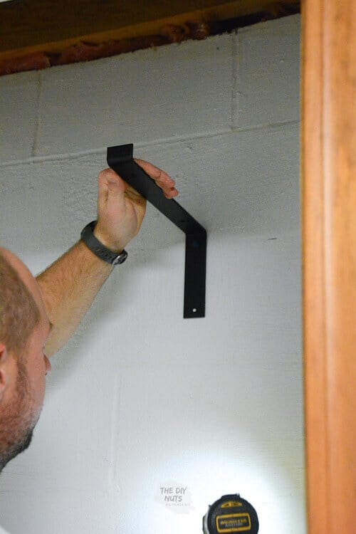 Use a cordless drill to attach farmhouse shelving brackets