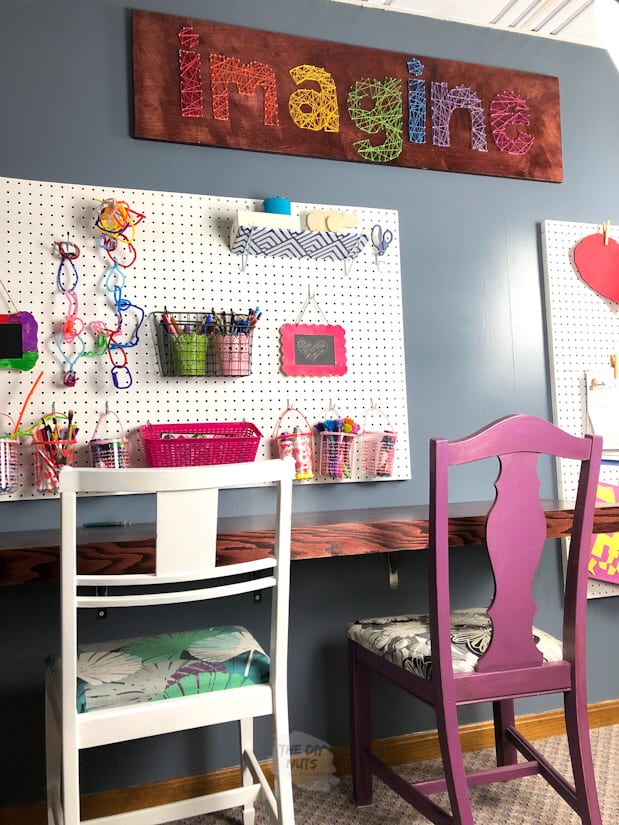 homeschool room with floating desk, white chair, purple chair, pegboard and large word art