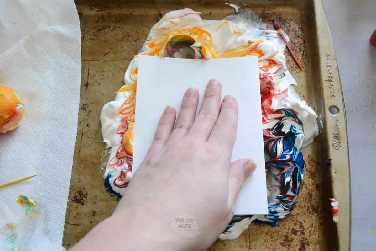 hand rubbing the back paper into marbled shaving cream
