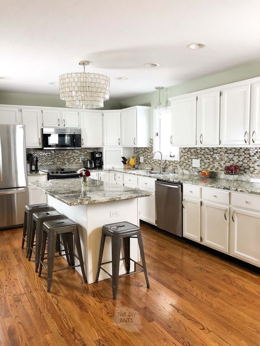 White painted kitchen cabinets with gray stools and light neutral green painted walls.