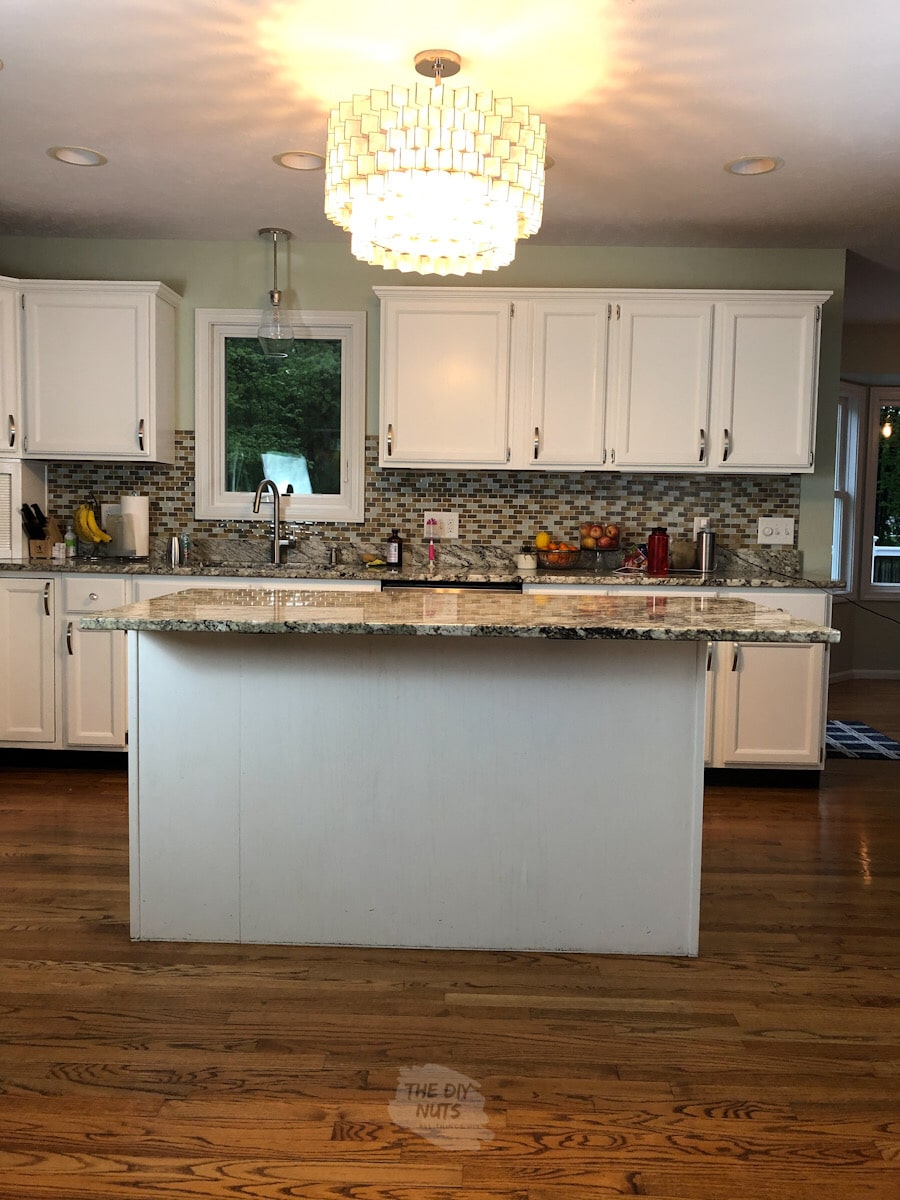 white painted oak kitchen cabinets with glass tile backsplash and capiz shell chandelier.