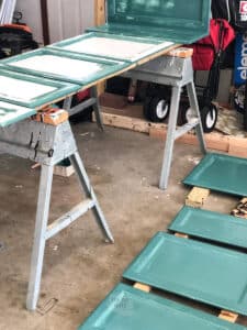 cabinet doors on saw horses and on floor with green paint.