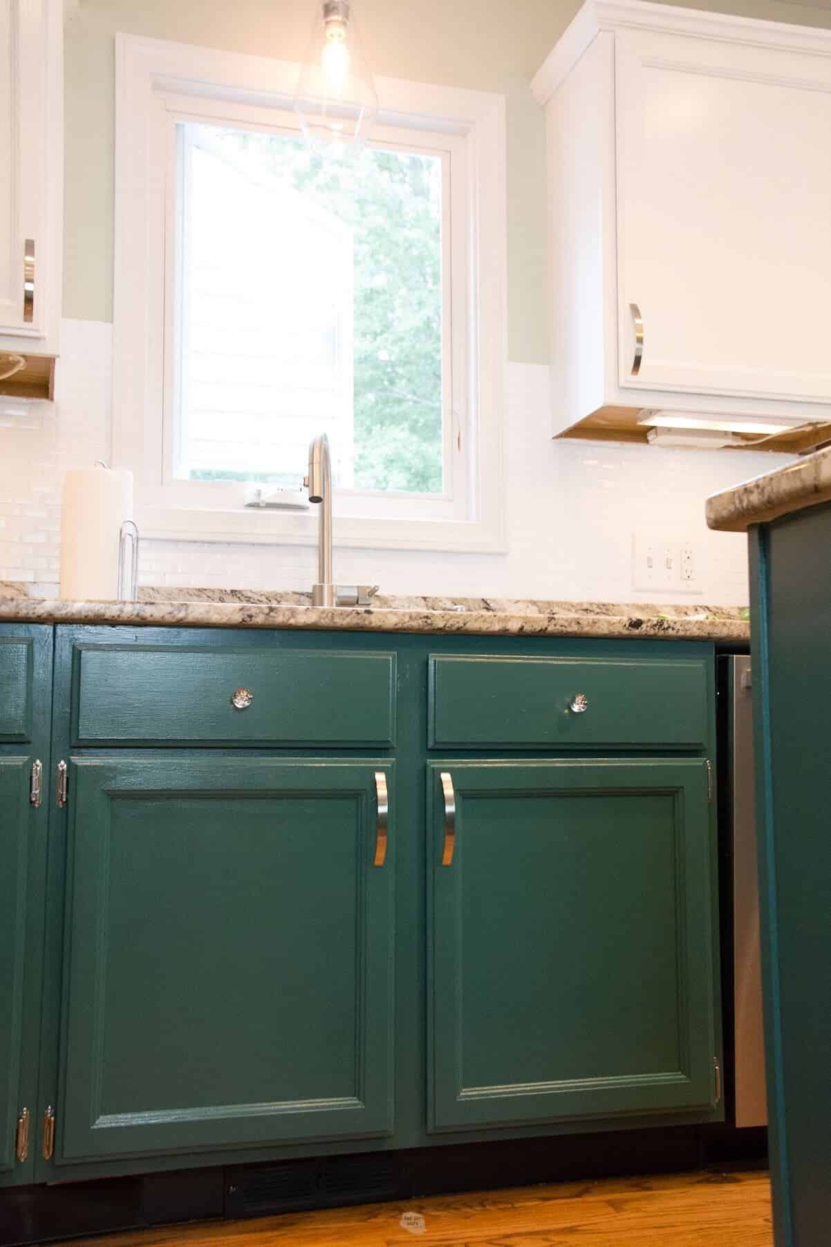 green lower kitchen cabinets and white upper cabinets by kitchen sink.