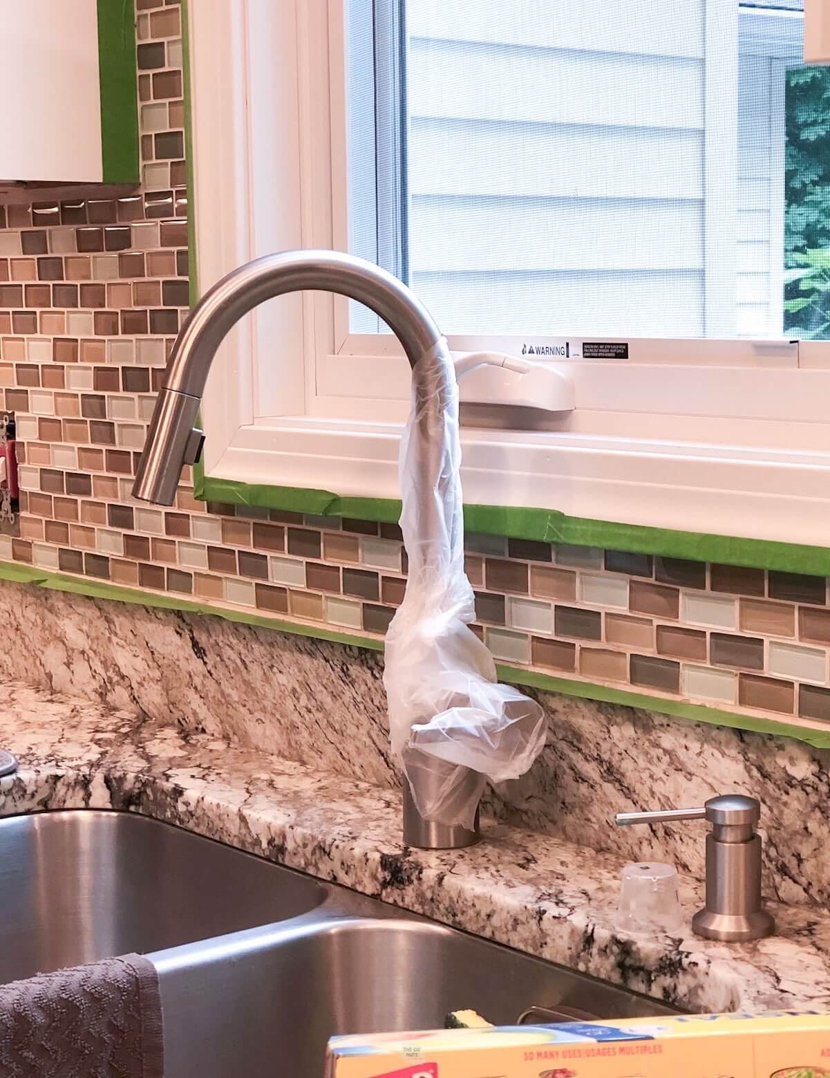 faucet wrapped in Cling Wrap to help with paint prep of tile.