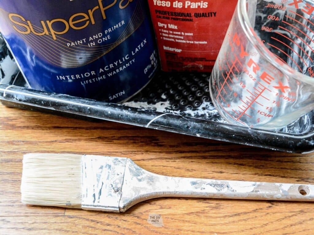 paint brush, paint, plaster of paris and measuring cup for chalk paint