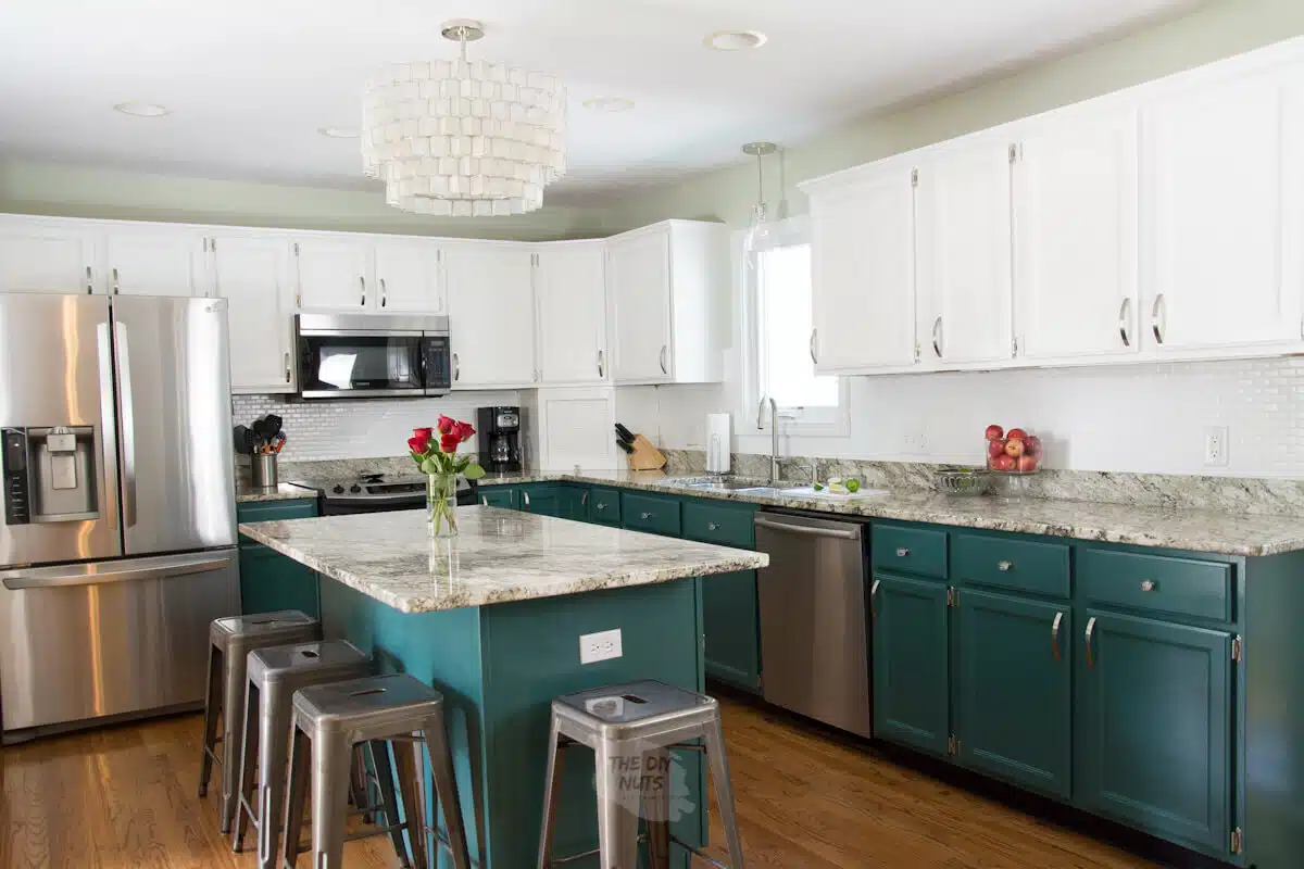 green and white kitchen with chandelier and metal bar stools.