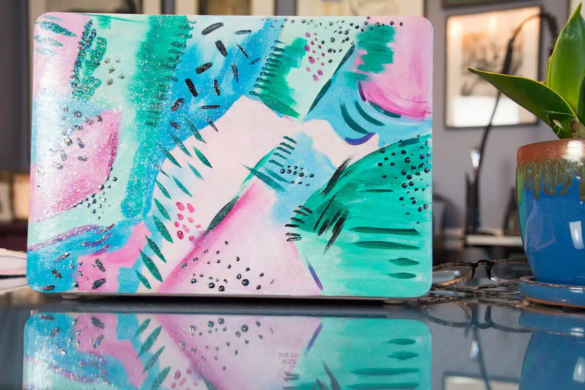painted laptop case with abstract design sitting on DIY desk.