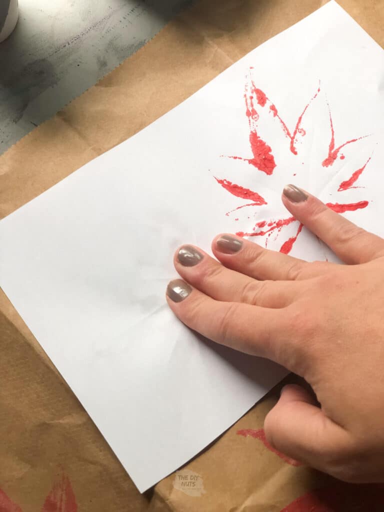fingers rubbing white paper on top of leaf