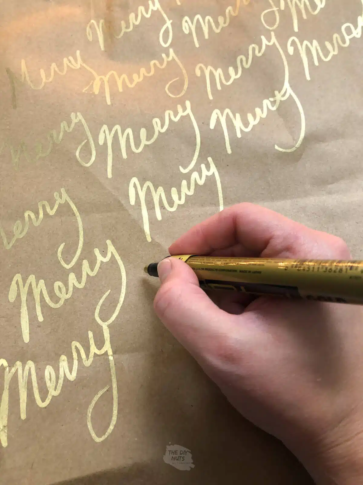 gold paint pen writing Merry on brown paper bag for easy homemade wrapping paper