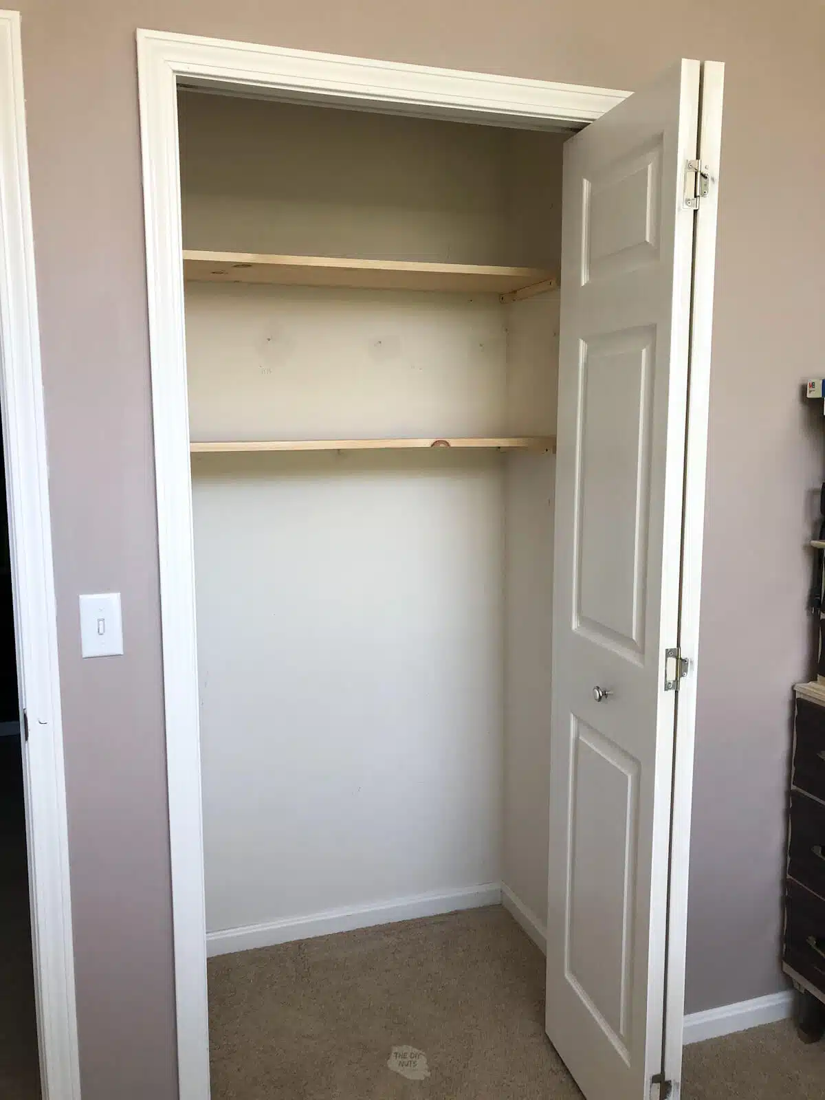 two wooden shelves in small closet installed on homemade wooden shelf brackets.