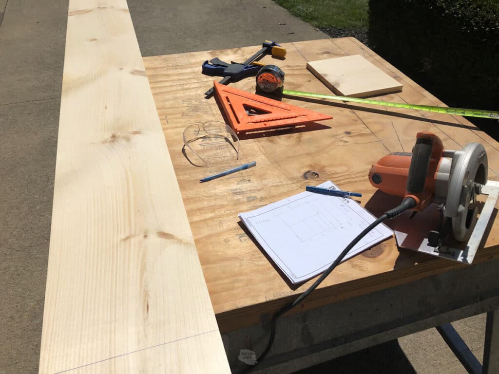 pine wood being ready to be cut for DIY shelves with tools and closet design sketch on sawhorses.