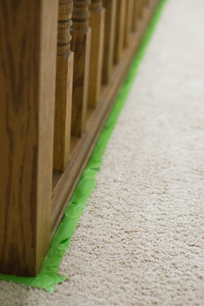 how to paint oak railing on carpet with green painter's tape under railing.
