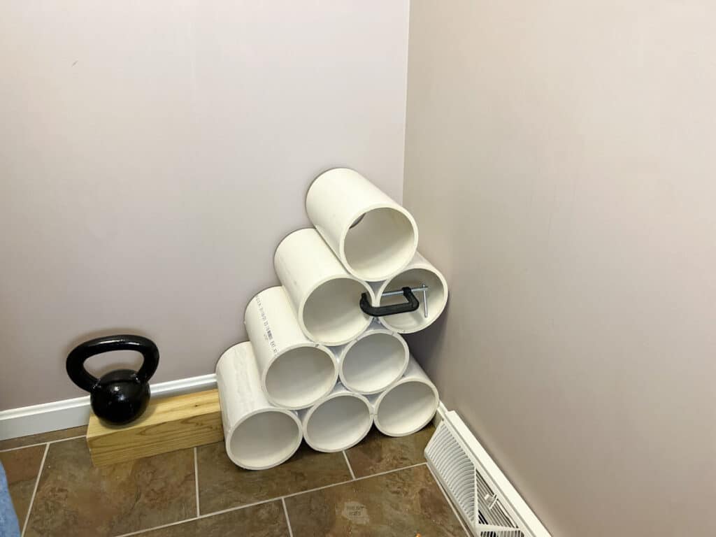 PVC pipe shoe rack drying in the corner of a room with weight and 2 x 4.