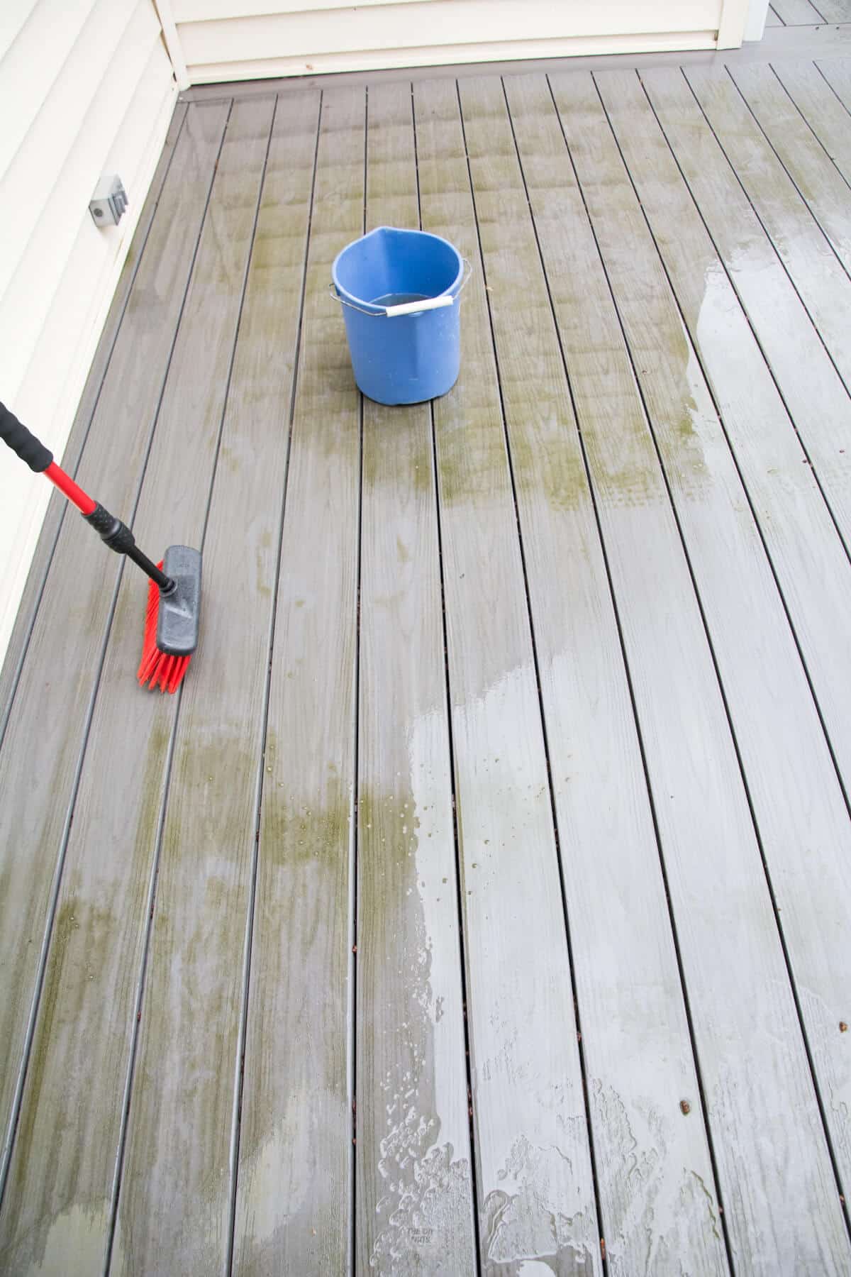 red deck brush with clean path on gray composite decking.