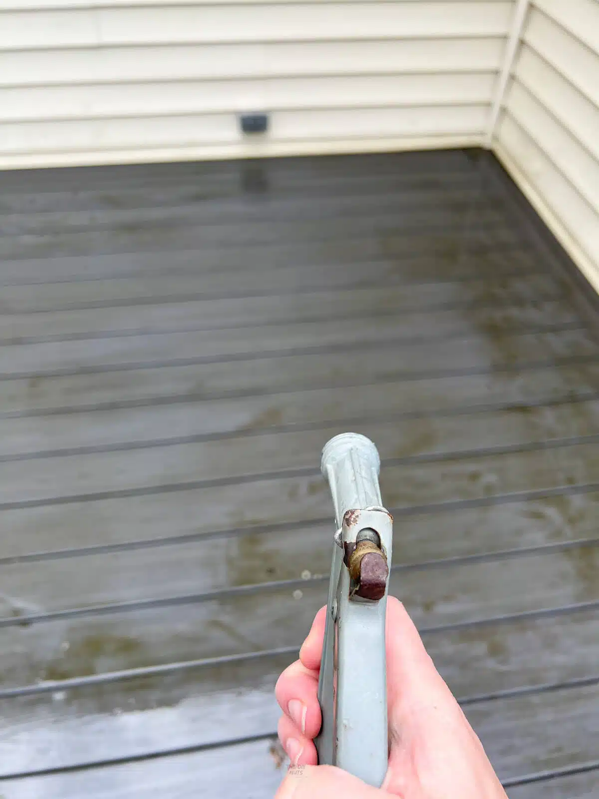hand holding spray on hose to wet deck down.