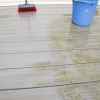 red brush showing clean path done with homemade deck cleaner.