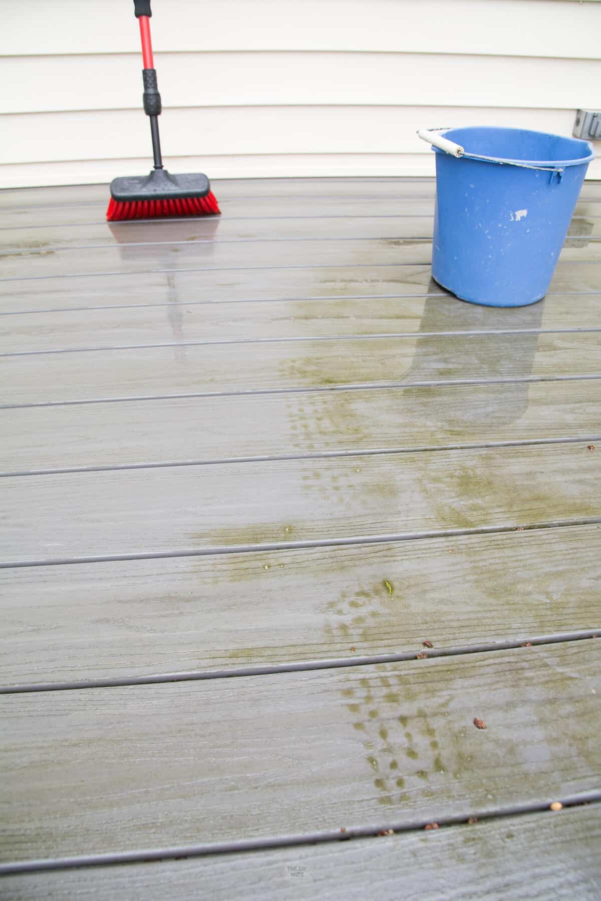red brush showing clean path done with homemade deck cleaner.
