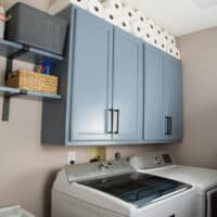 DIY laundry room wall cabinets and open shelving over the washer, dryer and utility tub.