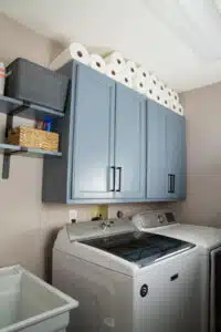 blue-gray laundry room wall cabinets and shelves above washer and dry.