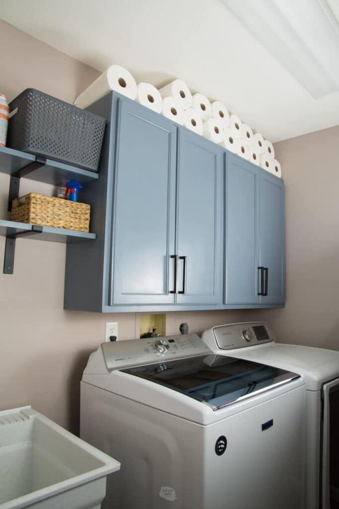 DIY laundry room wall cabinets and open shelving over the washer, dryer and utility tub.