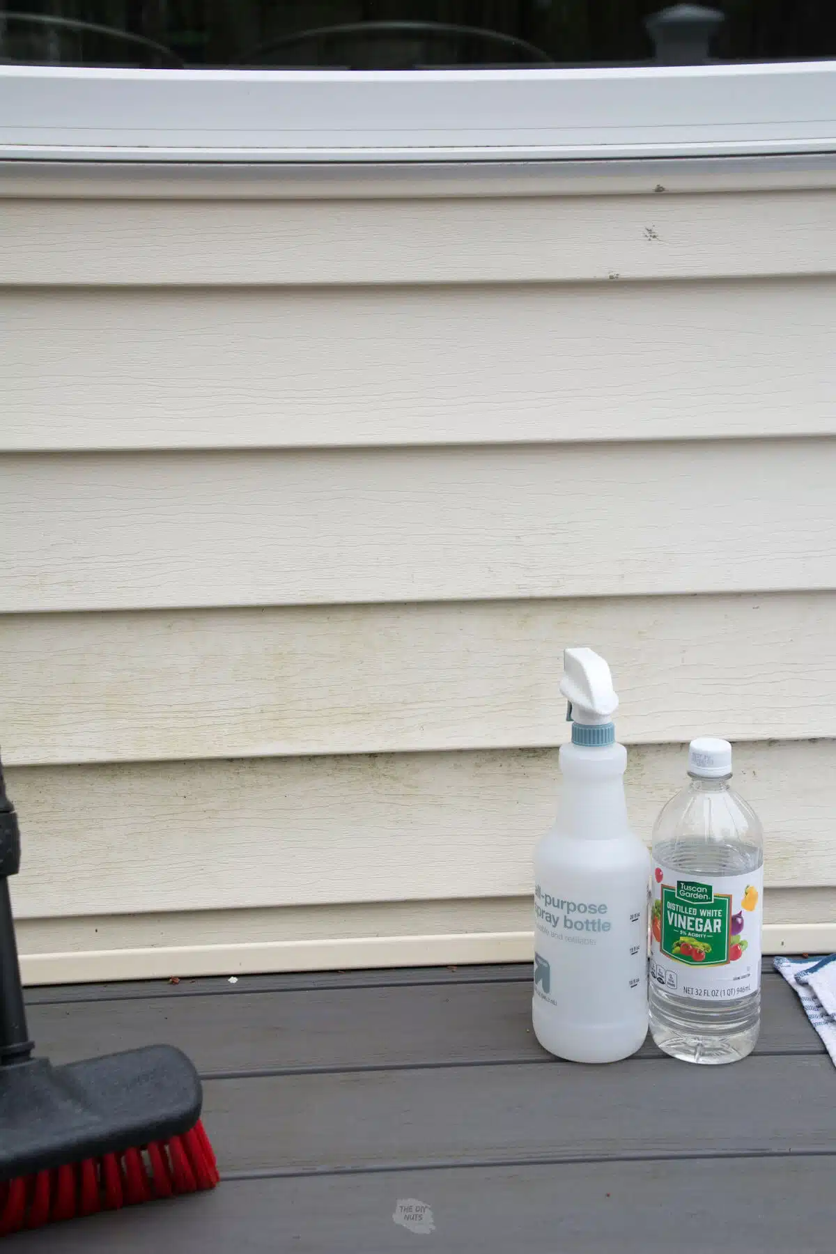 spray bottle with cheap white vinegar and brush in front of dirty siding.
