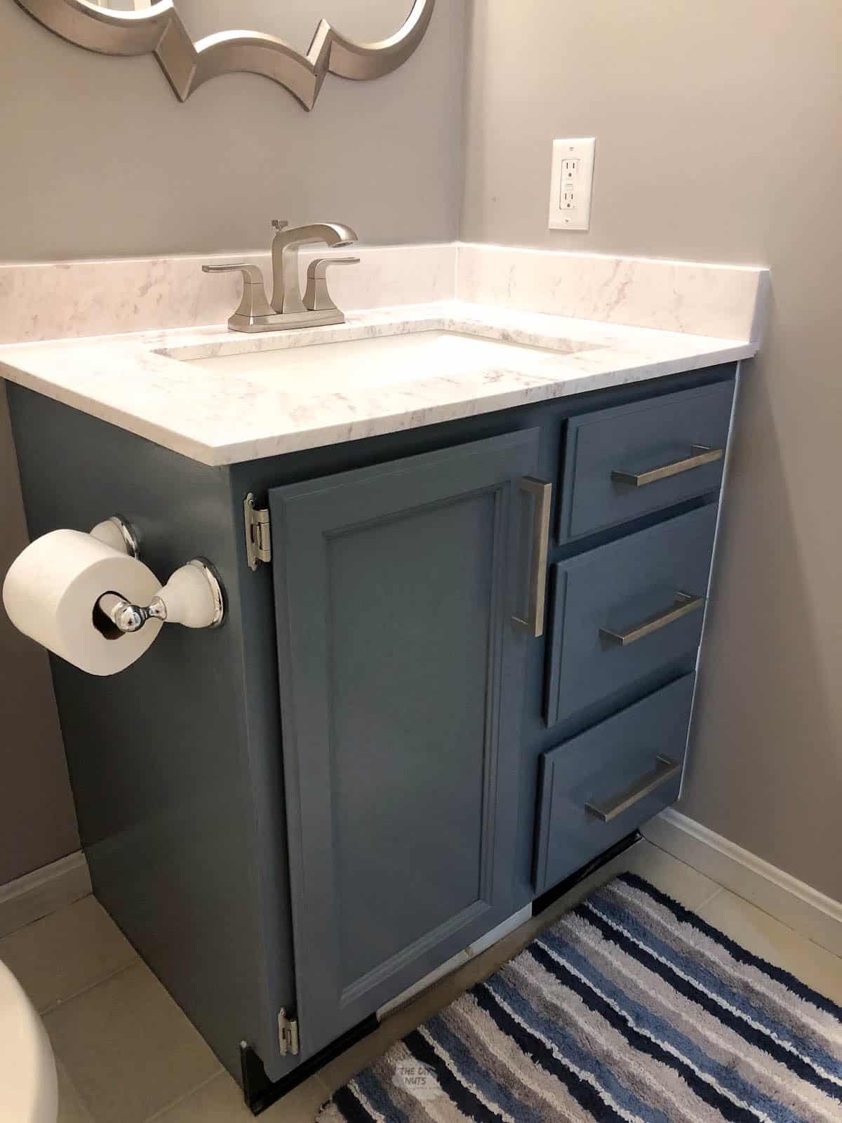 bathroom cabinets painted blue with countertop and silver faucet.