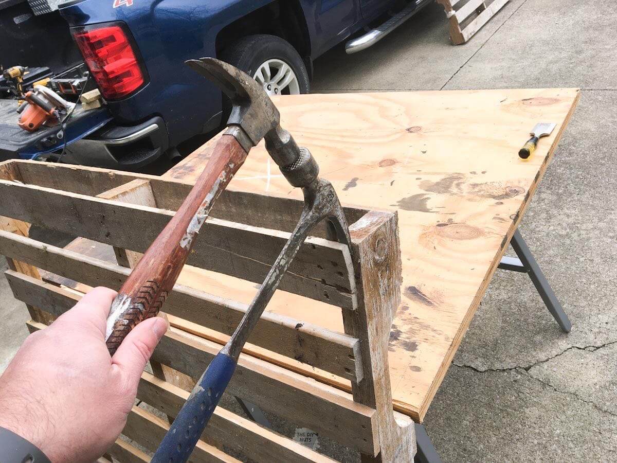 Two claw hammers break apart a pallet.