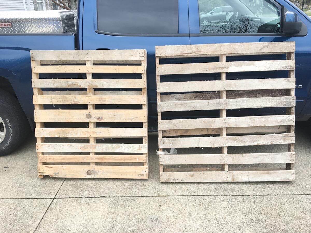 two wood pallets leaning against blue truck.