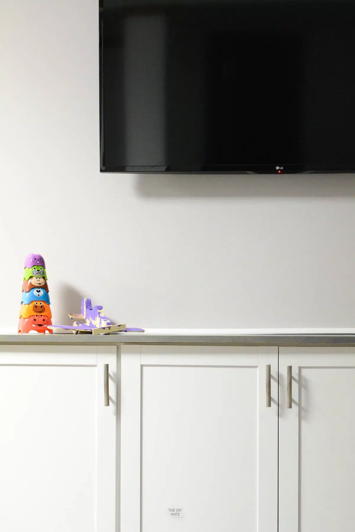 DIY Basement Makeover using white cabinets to create DIY built-ins below tv.