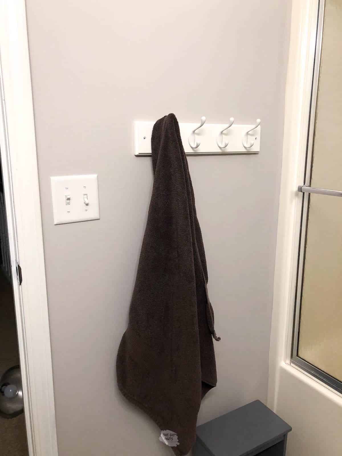 brown towel hanging on bathroom hook half way up the wall.