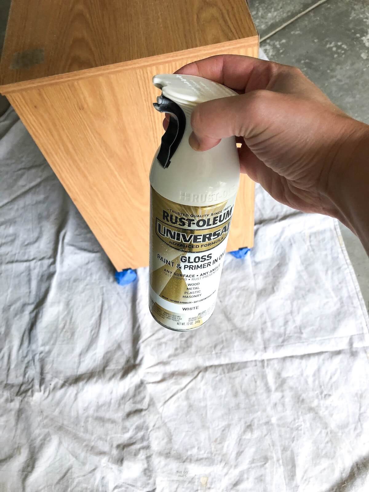 hand holding Rustoleum spray paint in front of oak file cabinet.
