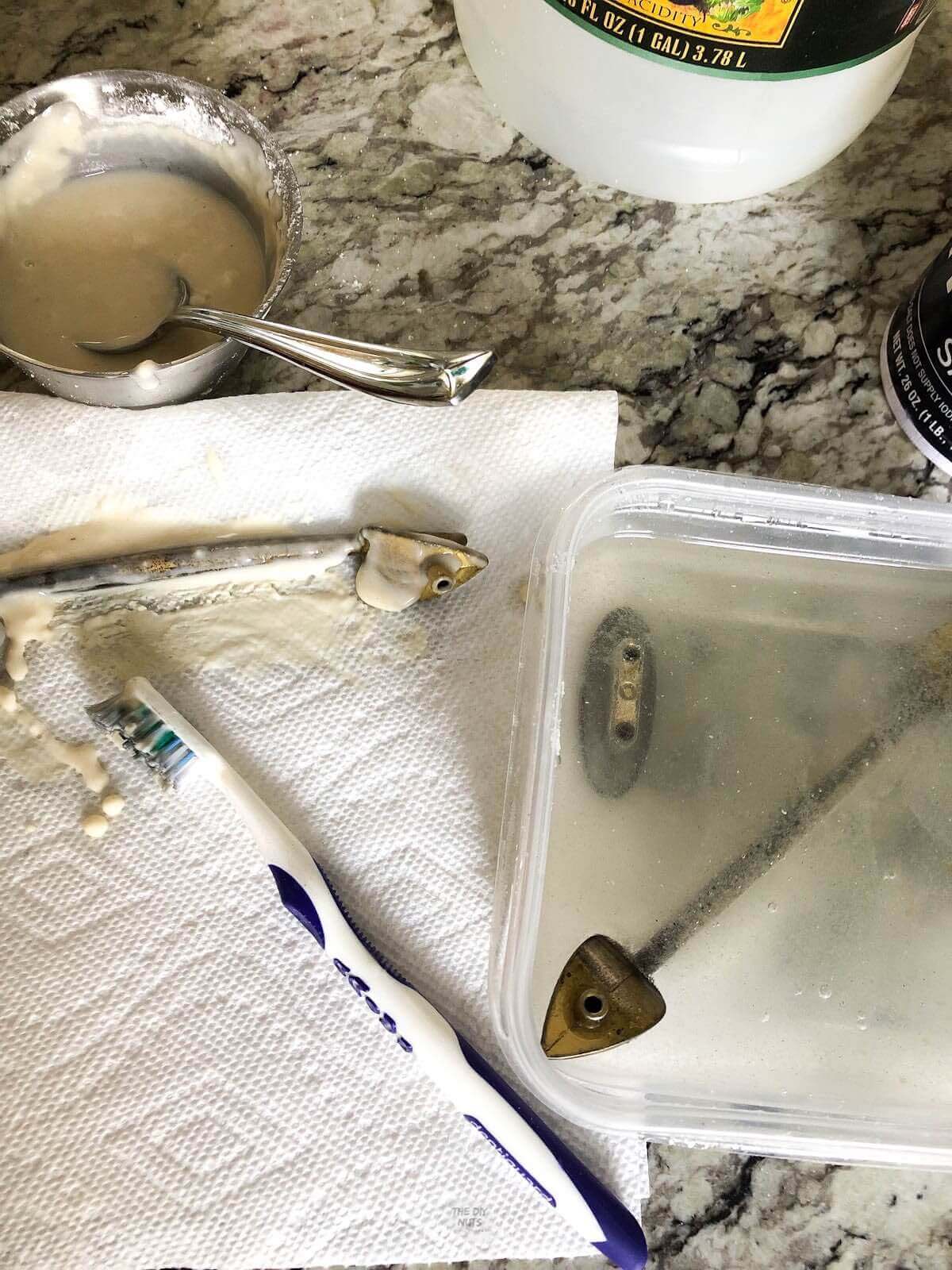 brass hardware soaking in vinegar and salt with toothbrush on paper towel.