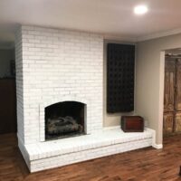 painted brick fireplace with wood flooring.