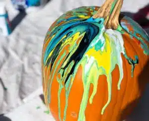 green, yellow and white paint poured over pumpkin.