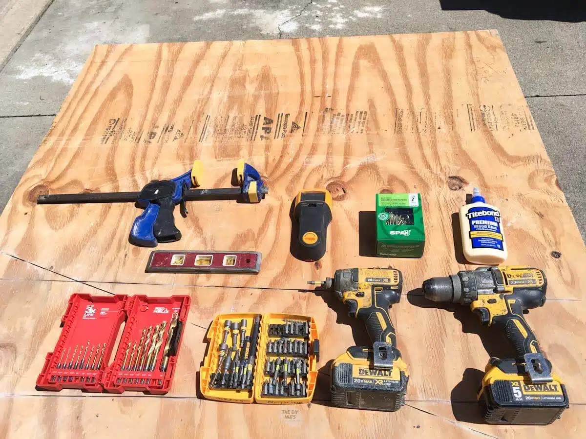 Tools used to build DIY wooden shelves in closet on plywood outside.