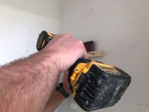 drill attaching wooden pine scrap to wall in closet.
