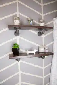 industrial pipe shelves on bathroom wall with herringbone pattern.