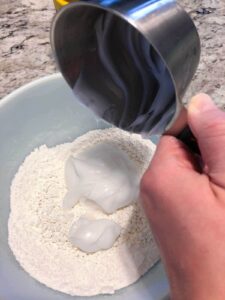 1 cup of lotion being added to 3 cups corn starch in mixing bowl.
