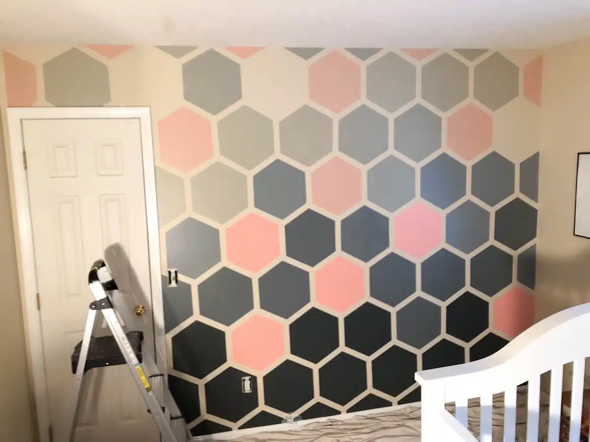 ladder in front of door and ombre hexagon painted wall.